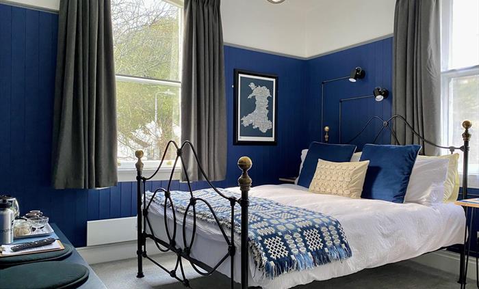 A bed with a blue and white Welsh blanket in a guest bedroom at Crafnant House